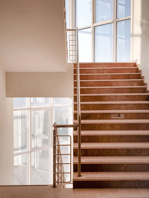 Escalier en béton avec rambarde métallique près d'une baie vitrée