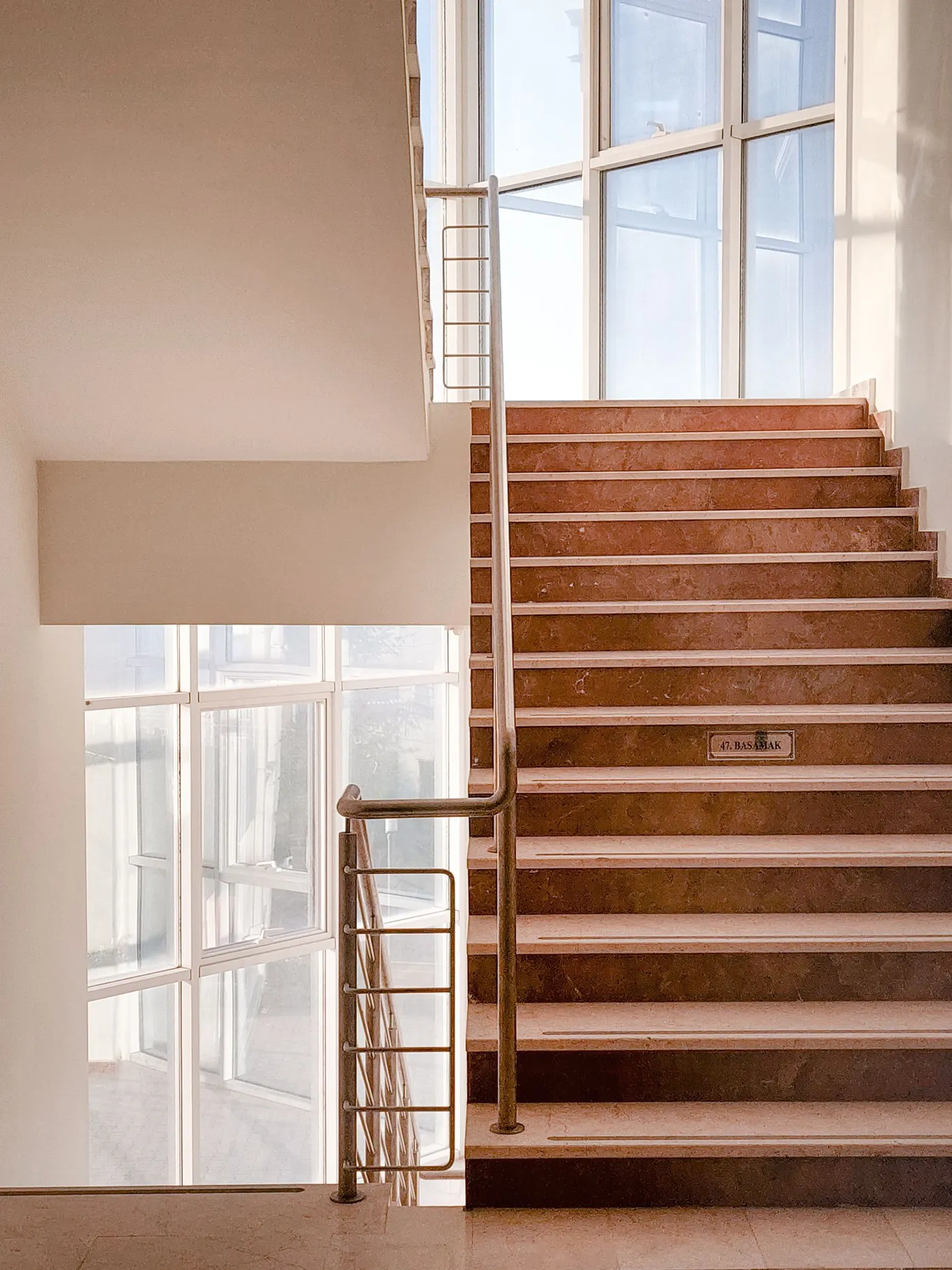 Escalier en béton avec rambarde métallique près d'une baie vitrée