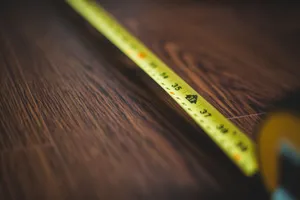 Mètre ruban déroulé sur un parquet en bois